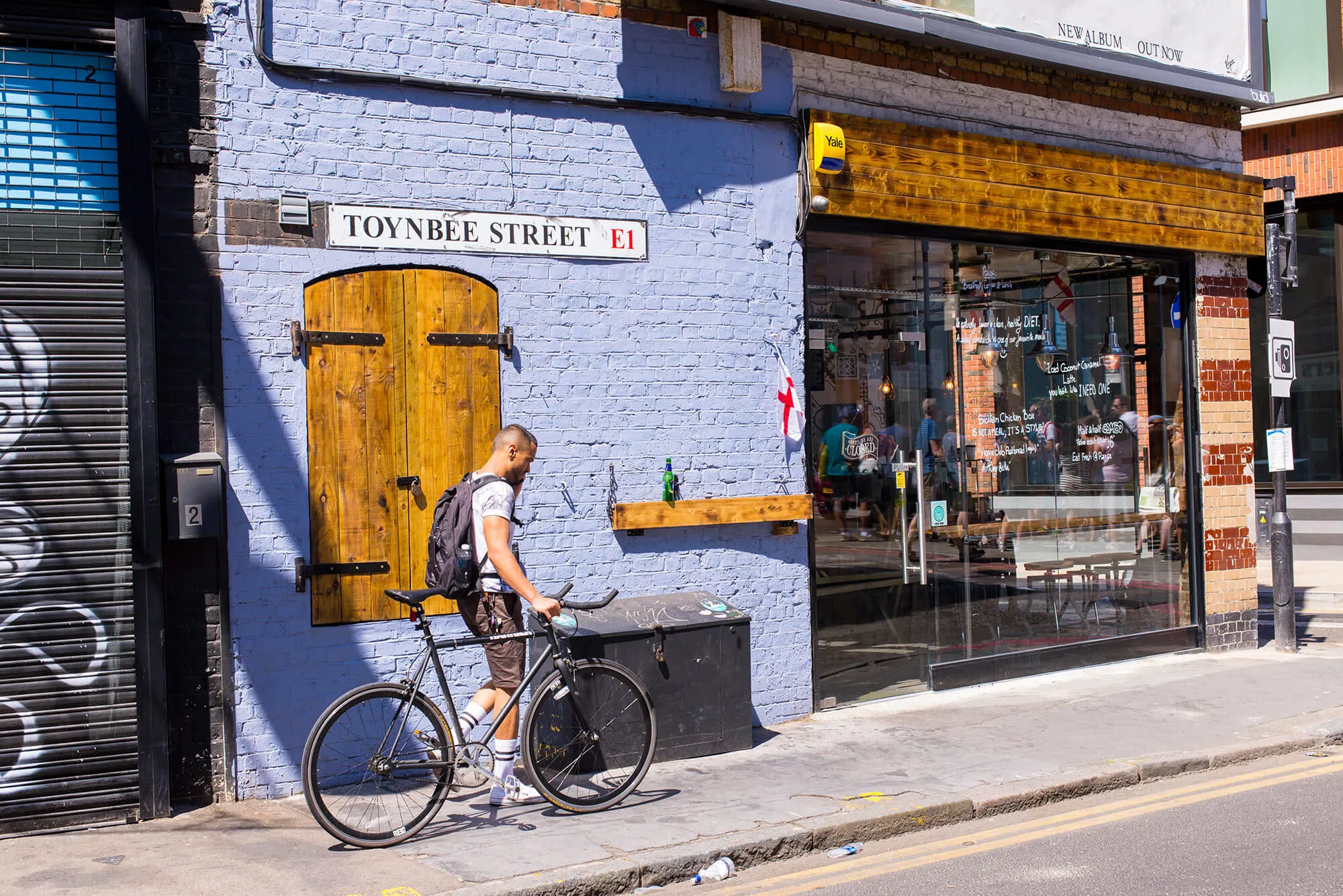 A man pushing his bicycle past a shop and talking on his phone.